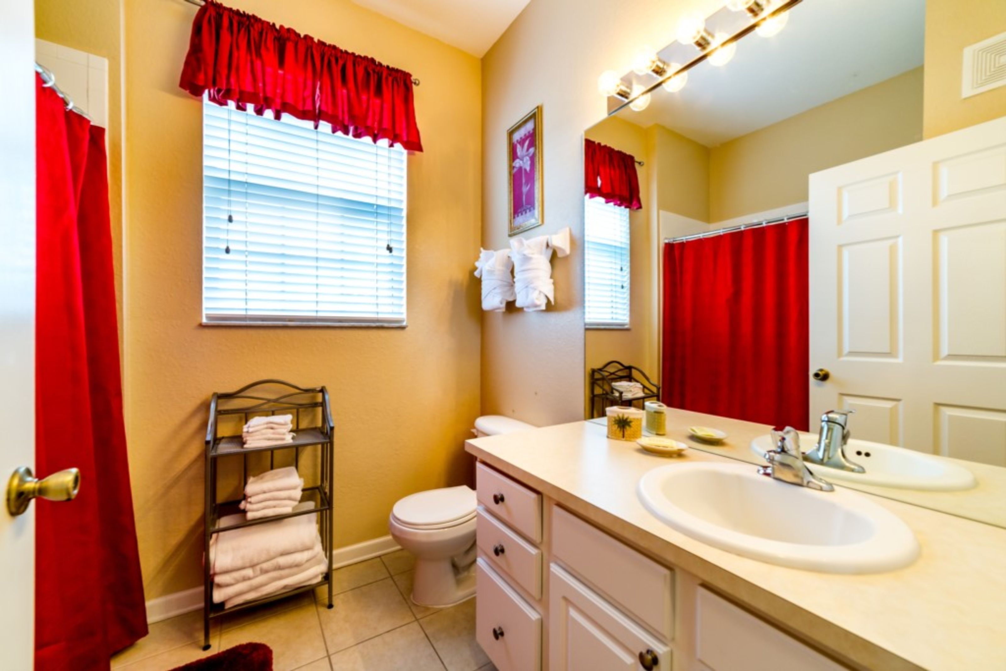 A bathroom with a white sink, a toilet, a towel rack, and a window with blinds.