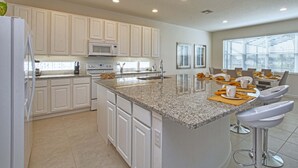 Una cocina moderna con armarios blancos, encimeras de granito y electrodomésticos de acero inoxidable.