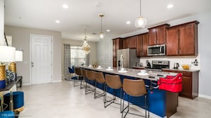 A modern kitchen with a central island, stainless steel appliances, and wooden cabinets. - Orlando Newest Resort Community Town Home (Lake Buena Vista)