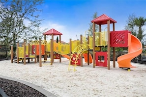Un parque infantil con un tobogán, estructuras para escalar y una zona de arena.
