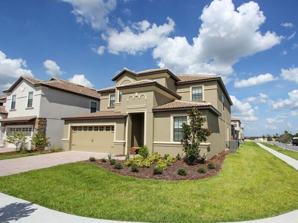 A two-story house with a garage, a front yard with landscaping, and a clear blue sky.