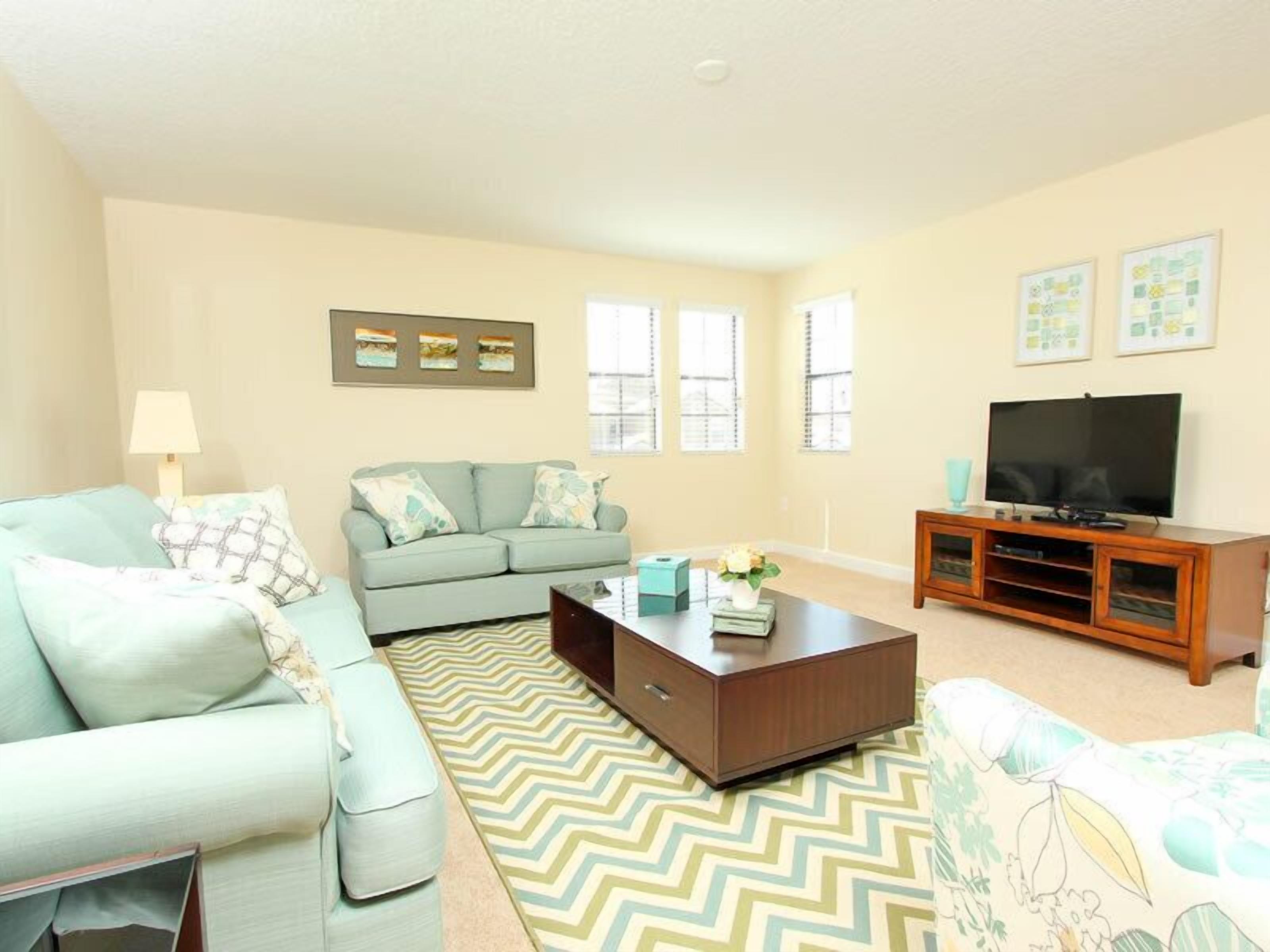 A living room with a sofa, coffee table, TV stand, and decorative pillows.