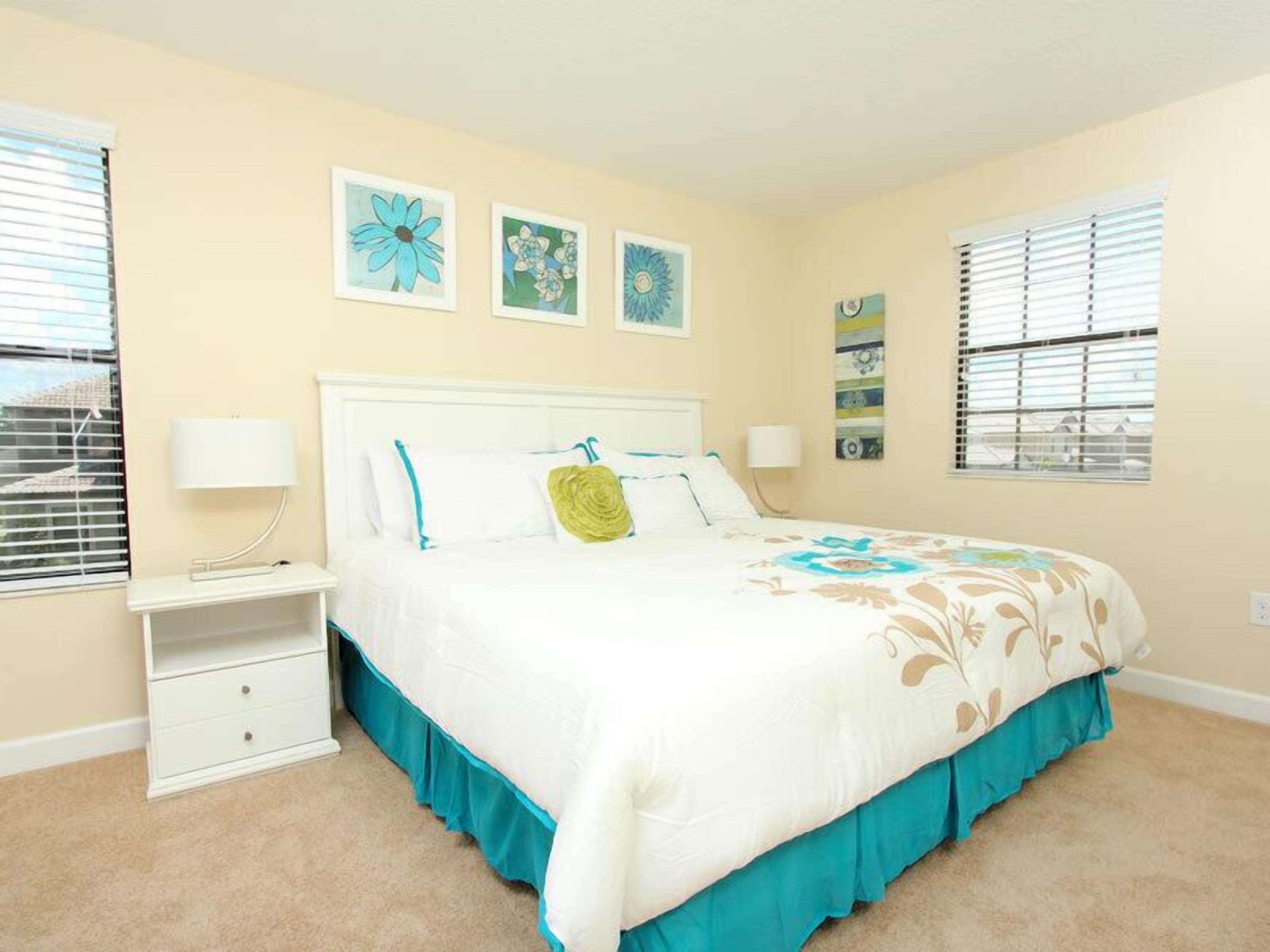 A bedroom with a bed, nightstands, and wall art.