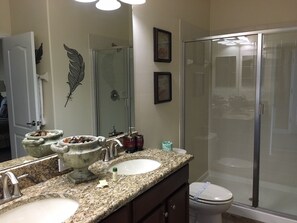 A bathroom with two sinks, a shower, and a toilet.