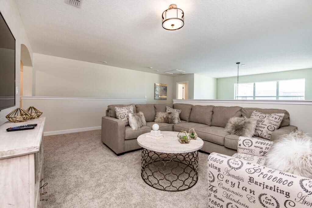 A living room with a sectional sofa, a round coffee table, and a decorative wall hanging.