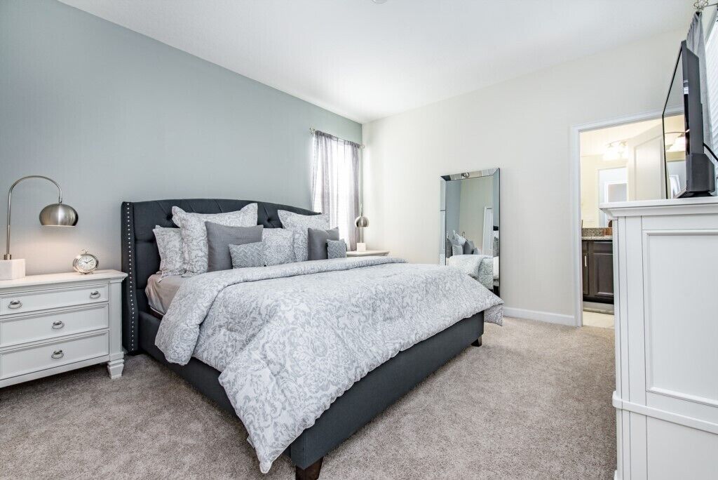 A bedroom with a bed, bedside tables, a dresser, and a mirror.