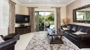 A living room with a TV, leather sofa, and a ceiling fan. - Reunion Resort IHR 4070 (Kissimmee)