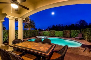 An outdoor pool area with a hot tub, surrounded by palm trees and hedges, under a night sky. - Reunion Resort IHR 4070 (Kissimmee)