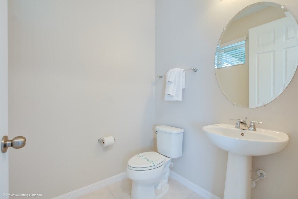 A bathroom with a toilet, sink, and mirror.