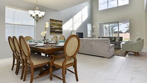 Un comedor amplio con una mesa y sillas de madera, una araña y un ventanal que ofrece luz natural.