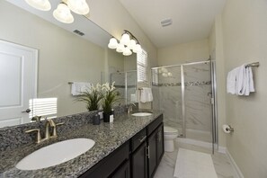 A modern bathroom with a double sink vanity, a glass shower enclosure, and a large mirror. - Champions Gate Villa -1624gmvdjgil (Davenport)