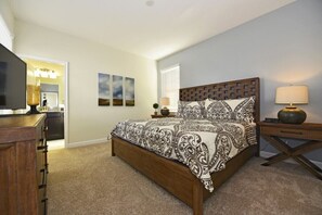 A bedroom with a wooden bed, a nightstand with a lamp, a dresser, and a TV. - Champions Gate Villa -1624gmvdjgil (Davenport)