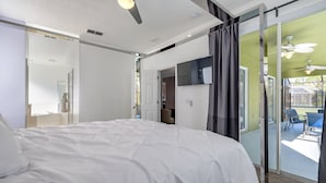 A bedroom with a large bed, a ceiling fan, a sliding glass door leading to a balcony with outdoor seating. - Emerald Island - IHR 4067 (Kissimmee)