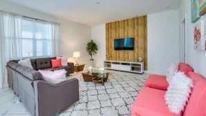 Un salon moderne avec un canapé, une table basse et un téléviseur fixé à un mur en bois.