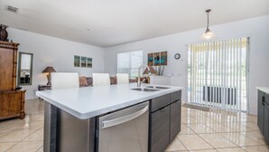 A modern kitchen with a large island, built-in appliances, and a dining area with a white table and chairs.