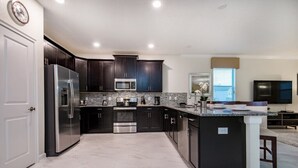 A modern kitchen with dark cabinets, stainless steel appliances, and a marble countertop. - 9000hs - Clone (Davenport)
