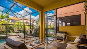Une pièce baignée de lumière, avec un mur de verre, une piscine et du mobilier d’extérieur.