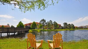 Two wooden Adirondack chairs facing a body of water with a bridge in the background and houses across the water. - Terra Verde IHR 3063 (Kissimmee)