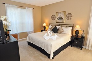 A neatly arranged hotel room with a large bed, two bedside tables with lamps, a television, and a window with sheer curtains. - Terra Verde IHR 3063 (Kissimmee)