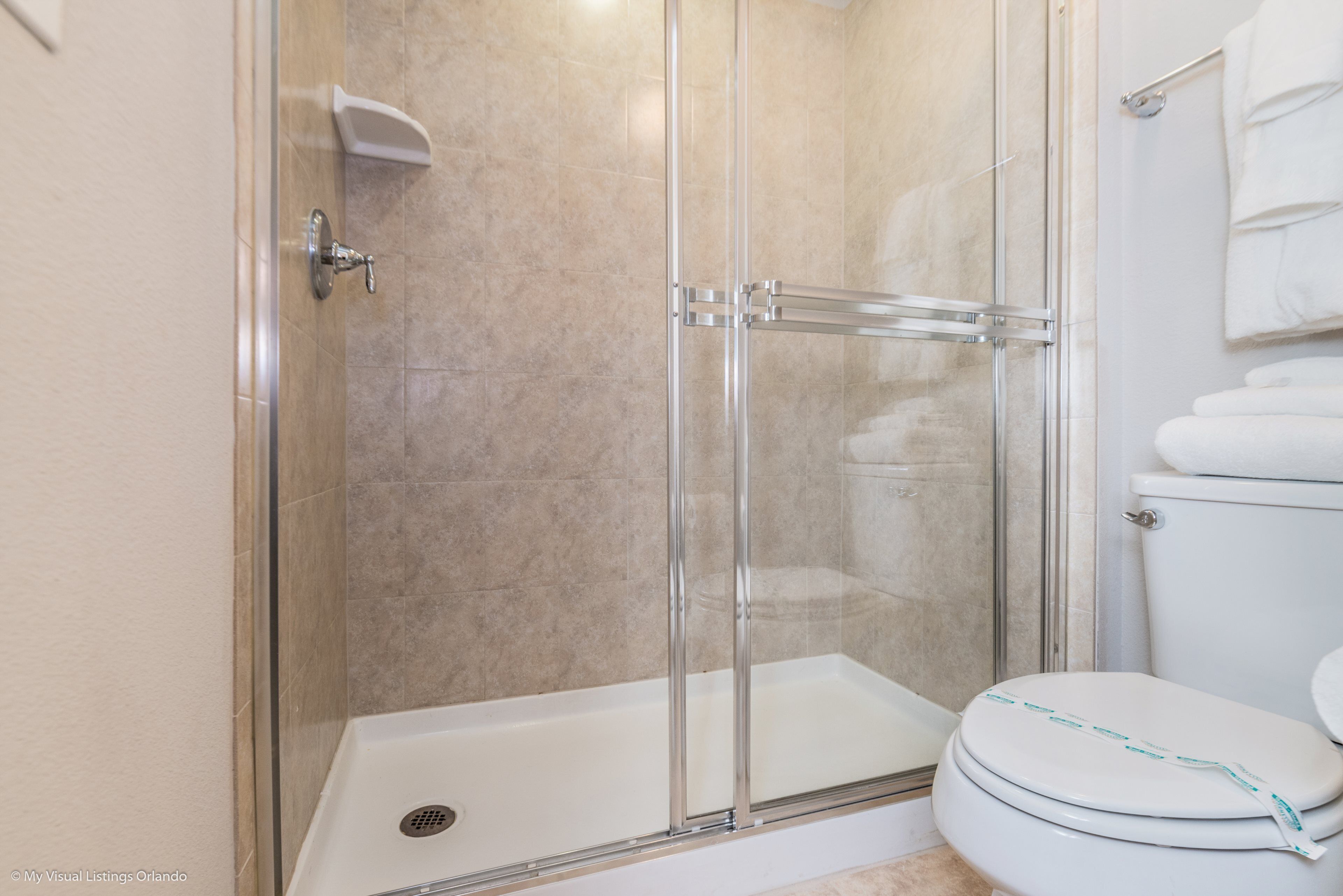 A bathroom with a glass-enclosed shower, a white toilet, and a white sink.