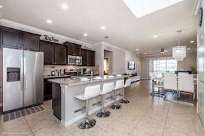 Enjoy meals in the kitchen with a central island and bar stools, adjacent to a dining area with a table and chairs.