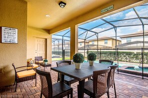 A covered patio with a table and chairs, a small pool, and a view of neighboring houses. - 2105mw Luxury 6 Bed Villa With Pool & Spa (Kissimmee)