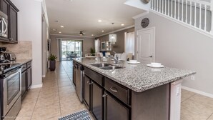 A modern kitchen with granite countertops, stainless steel appliances, and a large island with a sink. - 2105mw Luxury 6 Bed Villa With Pool & Spa (Kissimmee)