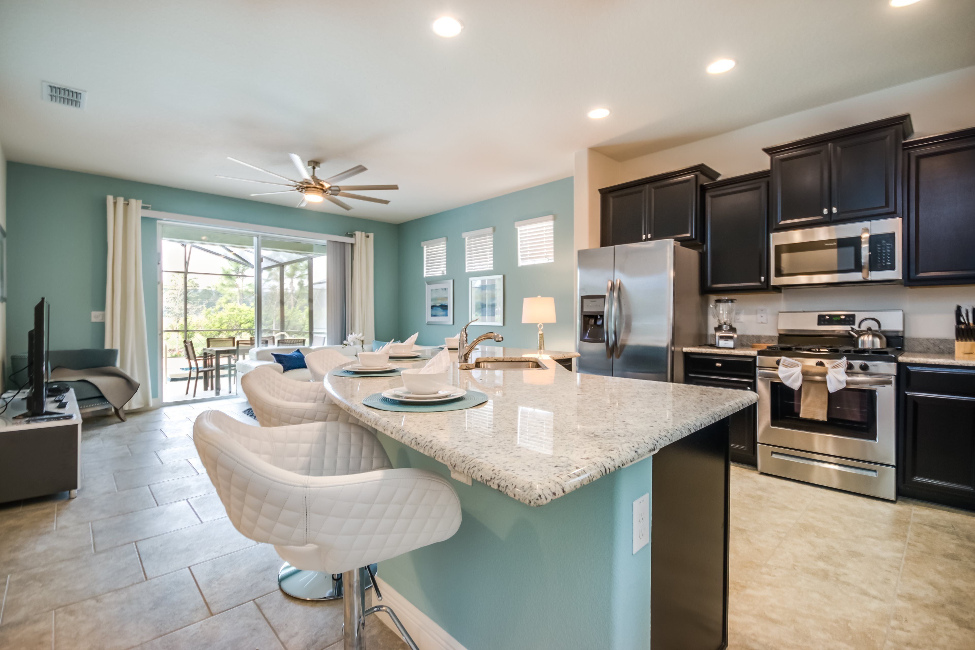 A modern kitchen with dark cabinets, stainless steel appliances, and a large island with bar stools.
