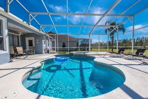 A covered outdoor swimming pool with a clear blue sky above, surrounded by lounge chairs and a patio area. - Highlands Reserve IHR 4077 (Davenport)