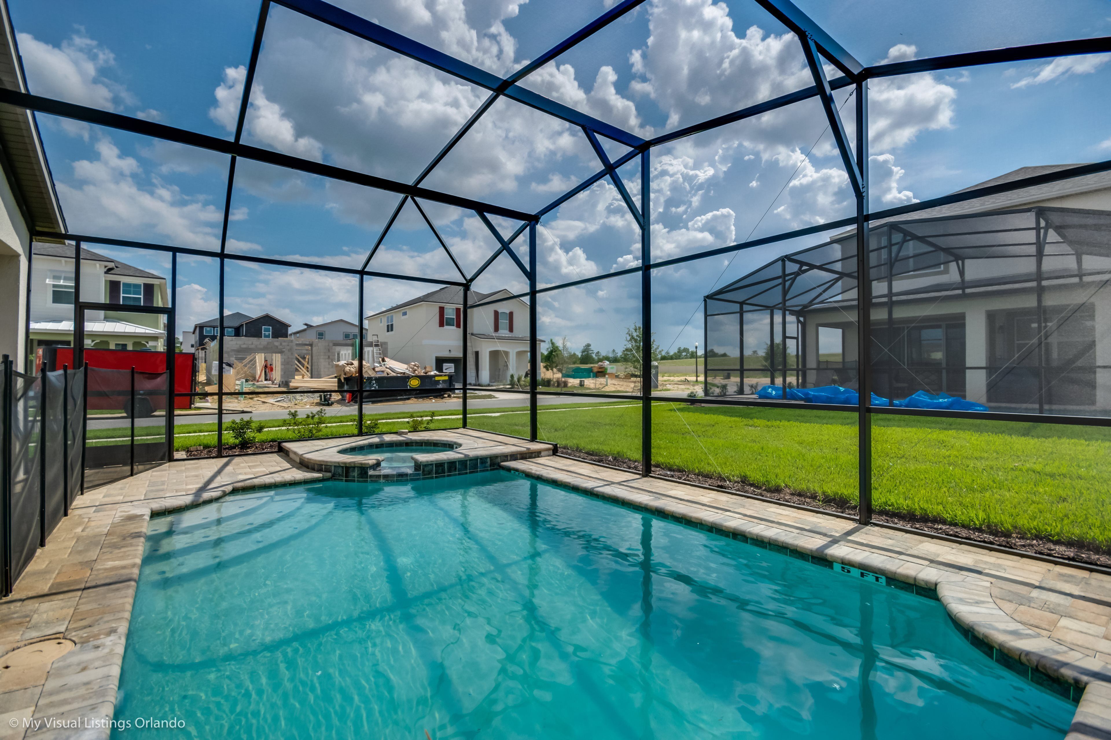 A swimming pool with a clear view of the surrounding houses and a grassy area.