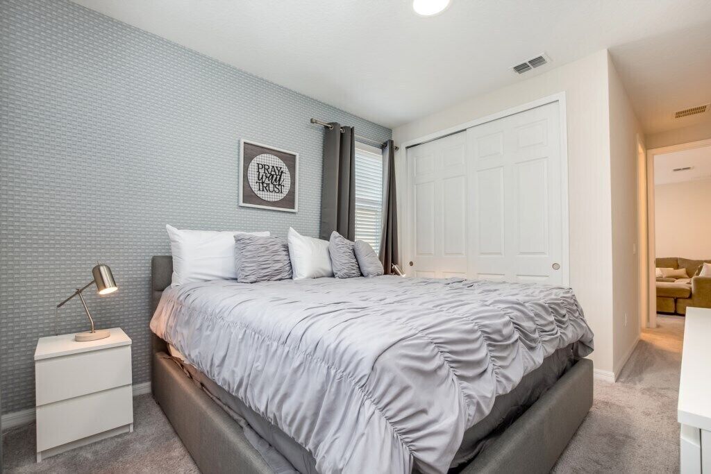 Un dormitorio con cama, mesita de noche y un cuadro en la pared.
