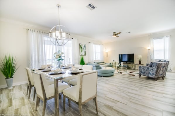 A spacious living room with a dining area, a large TV, and a patterned sofa.