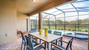 A covered patio with a pool, outdoor seating, and a view of the surrounding landscape. - Cool and Modern 6 Bed 4 Ba Villa Game Room Pool 5445 (Davenport)