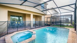 An indoor swimming pool with a hot tub, surrounded by a glass enclosure and patio furniture. - Cool and Modern 6 Bed 4 Ba Villa Game Room Pool 5445 (Davenport)