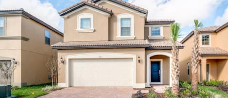 A two-story house with a beige exterior, a white garage door, and a blue front door.