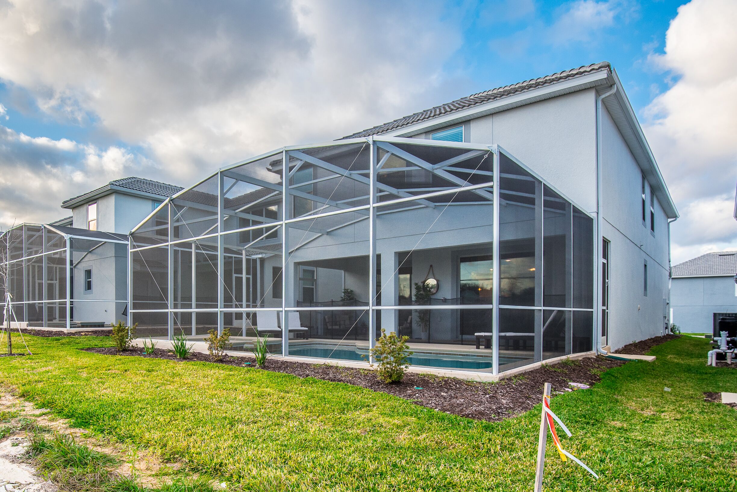 Une maison moderne dotée d’une grande extension en verre, d’une piscine et d’une pelouse bien entretenue.