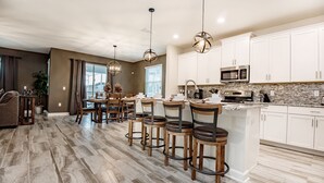 A modern kitchen with white cabinets, a granite countertop, and a built-in microwave. - 6 Bedroom Villa W Private Pool & Game Room (Davenport)