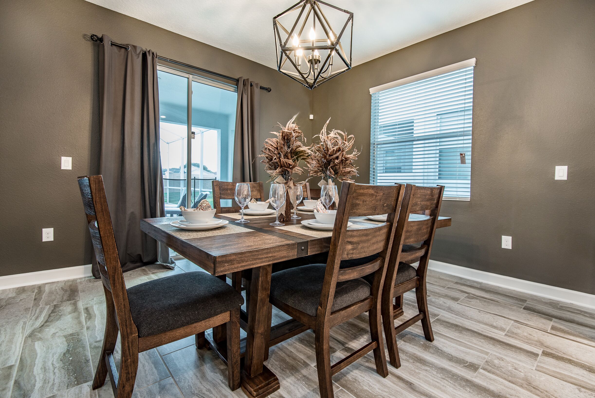 Un coin repas avec une table en bois dressée pour quatre personnes, entourée de chaises en bois foncé.