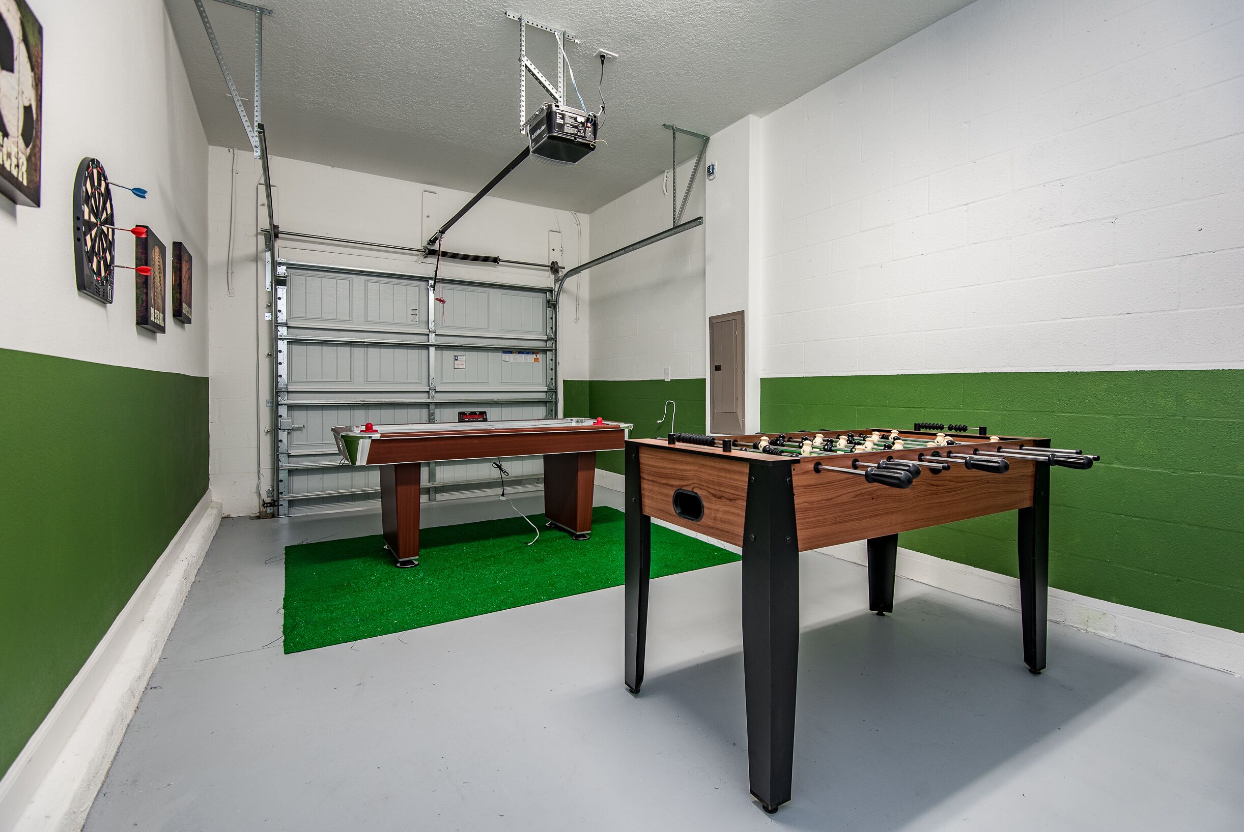 A room with a foosball table, dartboard, and a projector mounted on the ceiling.
