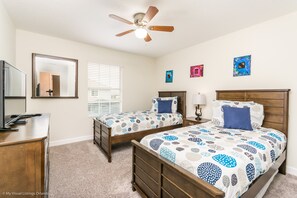 A bedroom with two beds, a ceiling fan, a dresser, a mirror, and artwork on the walls. - 3081juliet (Kissimmee)