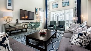 Una sala de estar moderna con un televisor grande, asientos cómodos y vistas al exterior.