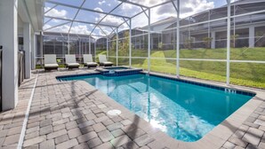 A swimming pool with a glass enclosure, lounge chairs, and a brick patio. - Ultimate 8 Bedroom Champions Gate (Davenport)
