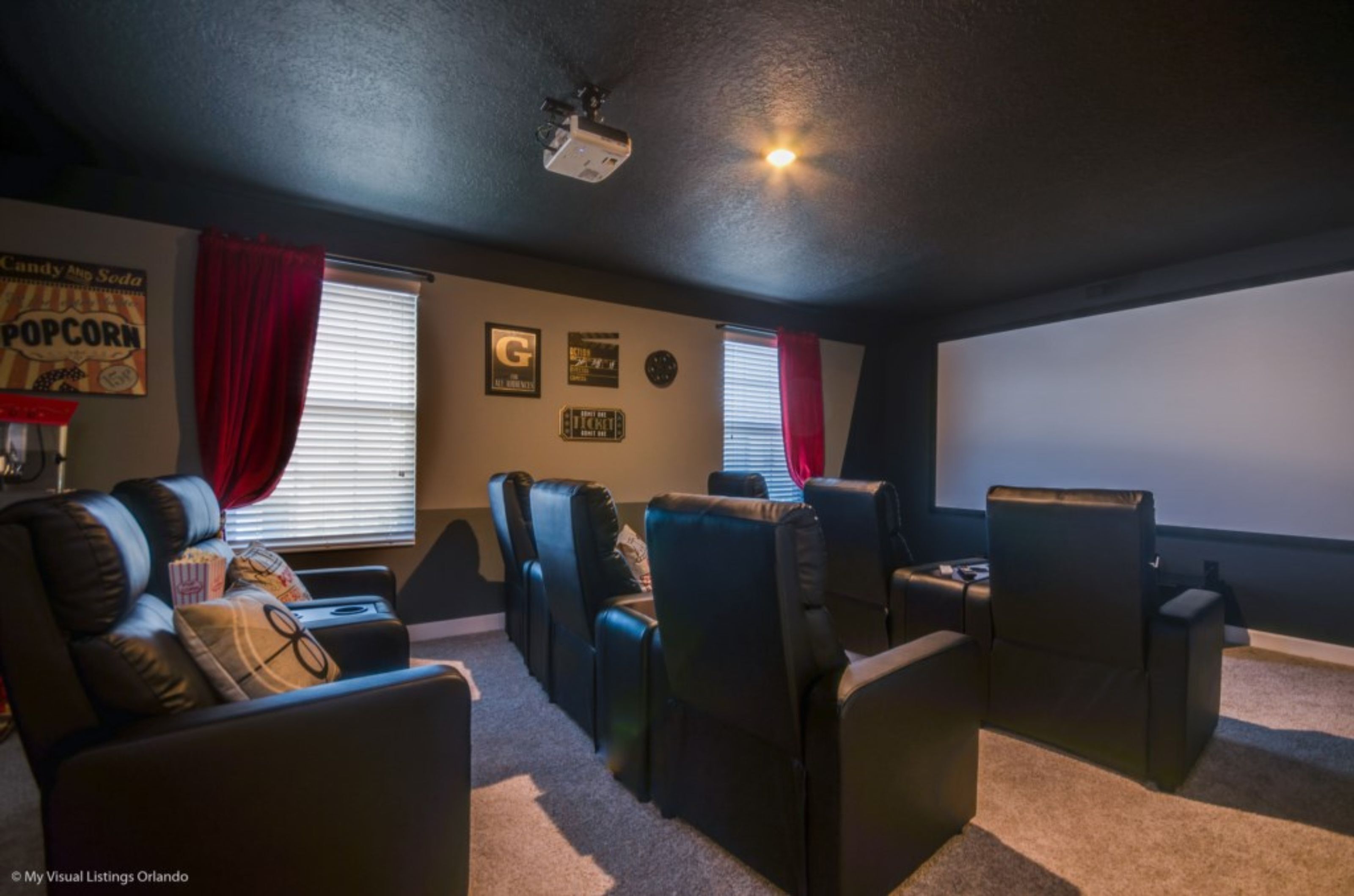 A home theater room with a projector, reclining chairs, and a large screen.