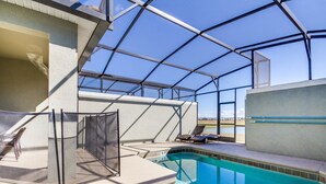 A covered outdoor swimming pool with a glass ceiling, lounge chairs, and a view of the landscape.