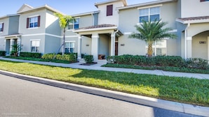 A row of townhouses with individual front doors, small front yards, and a clear sky.