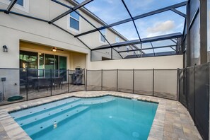 Una piscina con techo de cristal, un patio con mobiliario exterior y vistas al cielo.