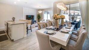 Una cucina moderna con isola centrale, zona pranzo con tavolo bianco apparecchiata per sei persone e un'ampia finestra con vista sulla città.