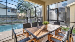 A covered patio with a pool, outdoor seating, and large windows.