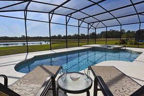 Una piscina con zona cubierta, sillas de descanso y una mesa con un cuenco.