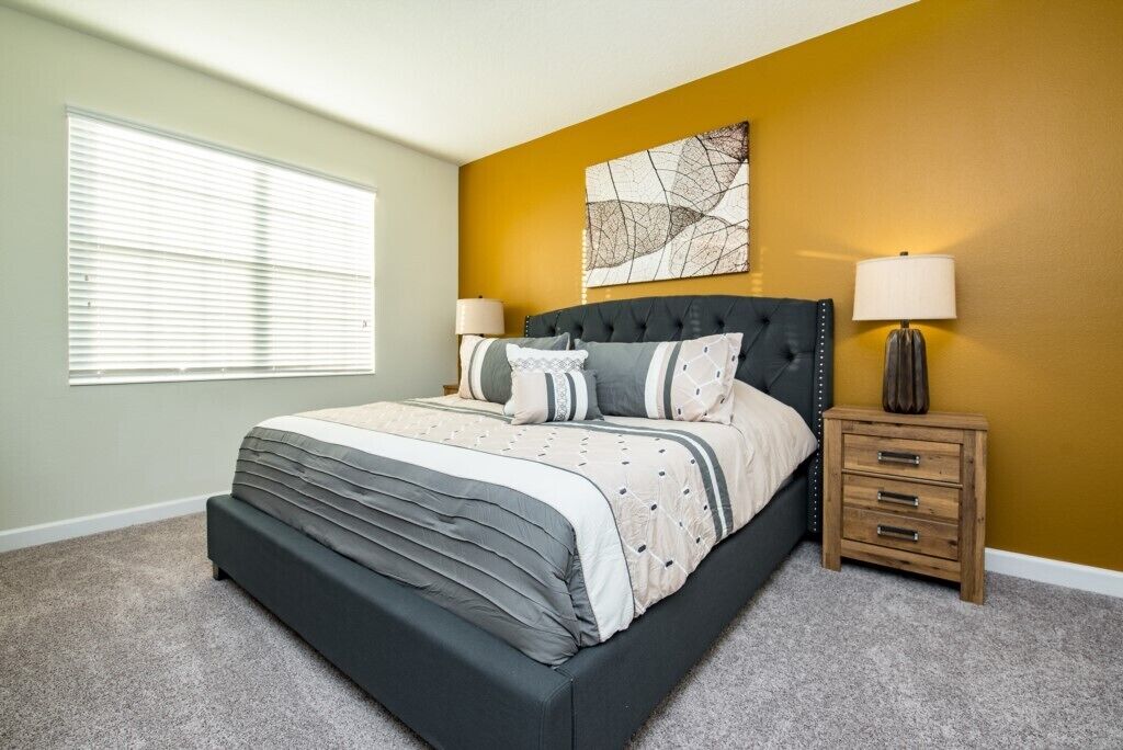 A bedroom with a bed, bedside tables, a window, and a wall with a painting.